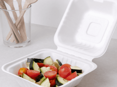 a white styrofoam container filled with tomatoes and cucumbers