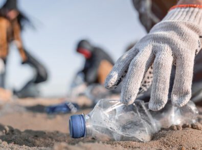 a person wearing a white glove is picking up a plastic bottle